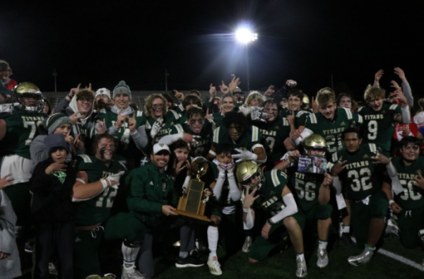 After the big win over Central, the football team crowds around the trophy for a victory photo.