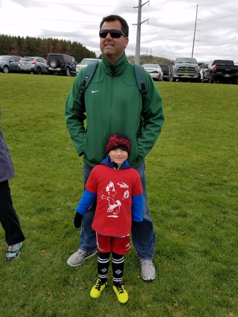 J. Carmien stands with his son M. Carmien at a soccer game that J. Carmien was coaching. 